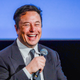 A photo of Elon Musk laughing while holding a microphone is shown.
